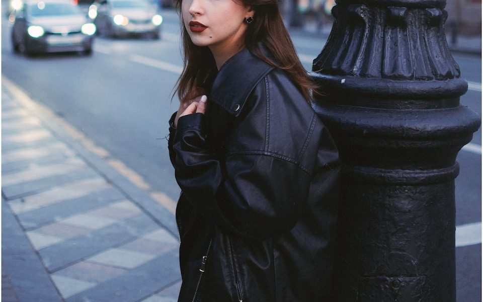 a woman leaning against a pole on a city street